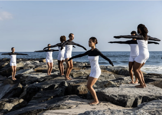 A group of people standing on rocks with arms out

Description automatically generated