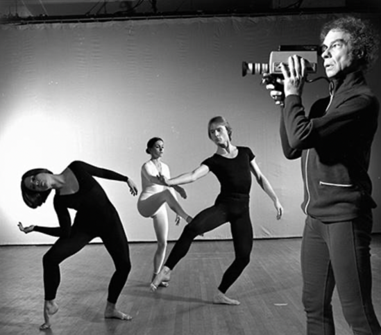 A person holding a camera to a group of dancers

Description automatically generated